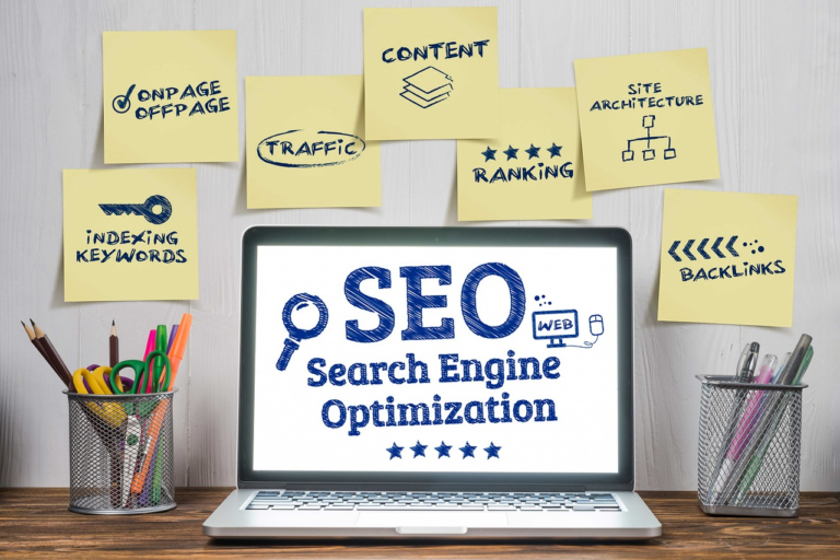 Laptop with SEO (Search Engine Optimization) on the screen surrounded by sticky notes with keywords like content, backlinks, ranking, and traffic.